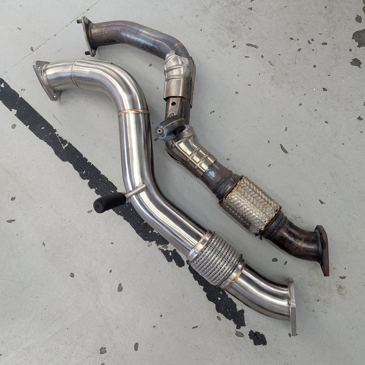 Two metal exhaust pipes on a concrete floor